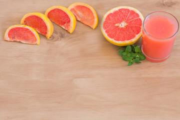 Glass of freshly squeezed grapefruit juice with sliced grapefruit background.