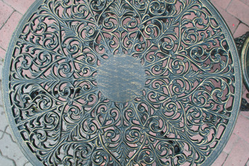 Forged table and chairs with ornament on the background of flowers in a cafe in the city of Bran, Romania