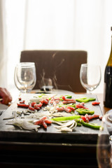Traditional Swiss winter meal. Raclette. The stone Raclette machine at the peak temperature of the furnace a bacon of organic green pepper, onion. Blurred background lights. Vertical. Food concept. - 