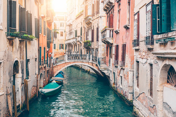Fototapeta na wymiar Narrow canal with boat and bridge in Venice, Italy. Architecture and landmark of Venice. Cozy cityscape of Venice.