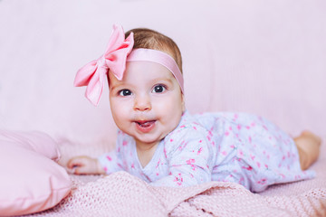 Baby lies in bed and shows tongue