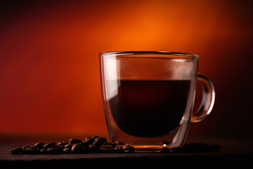Transparent Cup With Black Coffee (Americano) With Arabica Beans On A Red Background. Macro. Close Up. Rustic Style.
