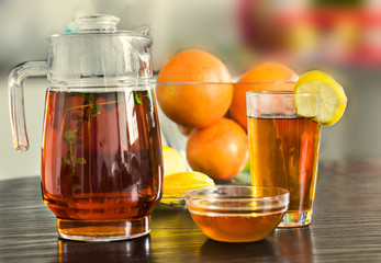 Pitcher and cup of hot black tea with mint, honey and lemons  the  background.
