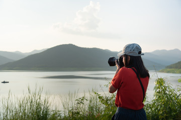 Obraz premium tourism woman hold camera for take a photo mountain and lake in journey trip