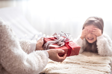 Christmas concept, Mom gives a gift to a little cute daughter, a place to text on a light background