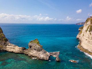 Naklejka premium Aerial view to beautiful arched rock in ocean on Atuh beach. Photo from drone. Nusa Penida, Bali, Indonesia