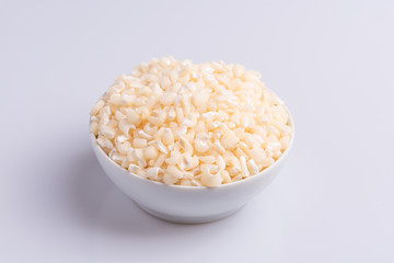 Dry uncooked white corn ingredient for Brazilian dessert sweet canjica / mungunza, white background, isolated, soft light. Festa Junina Party Brazilian Culture Concept Image.