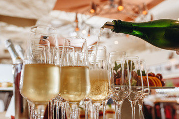Sommelier pours champagne from a bottle into a glass at the table in the restaurant.