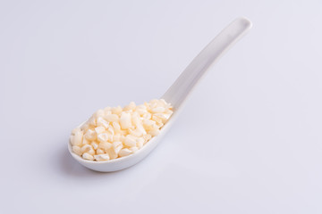 Dry uncooked white corn ingredient for Brazilian dessert sweet canjica / mungunza, white background, isolated, soft light. Festa Junina Party Brazilian Culture Concept Image.