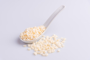 Dry uncooked white corn ingredient for Brazilian dessert sweet canjica / mungunza, white background, isolated, soft light. Festa Junina Party Brazilian Culture Concept Image.