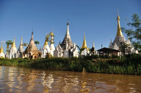 Ancient temple on shore of lake, Landscape of brown water of lake Inle with plenty of sacred temple stupas and payas on shore. Inle, Myanmar,Burma.