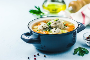 Meatball vegetable soup in a pot on light blue background. Selective focus, space for text.