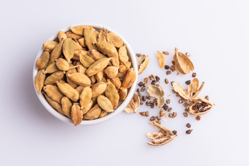 Dry Cardamom pod in a stone mortar, isolated on white background, latin term Elettaria cardamomum,  with copy space, angle view, soft light. 