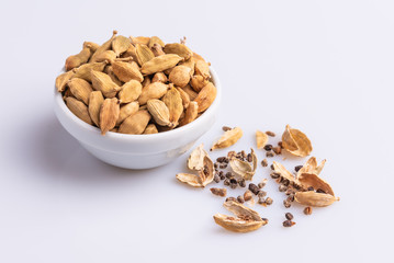 Dry Cardamom pod in a stone mortar, isolated on white background, latin term Elettaria cardamomum,  with copy space, angle view, soft light. 