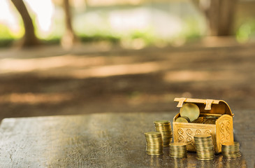 Small, open full treasure chest and columns of coins.