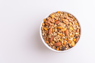 Fototapeta na wymiar Granola or muesli with nuts and rasins in a white bowl on a white background, top view, copy space, soft light