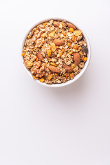 Granola or muesli with nuts and rasins in a white bowl on a white background, top view, soft light