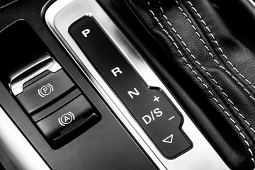 Automatic gear stick of a modern car. Maodern car interior details. Close up view. Car detailing. Automatic transmission lever shift. Black leather interior with red stitching. Black and white