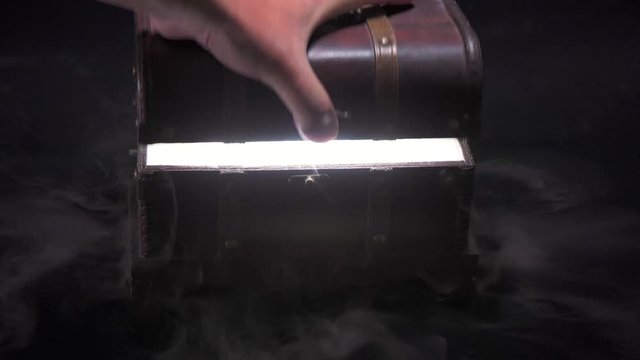 煙と光が漏れる宝箱を手で開く