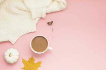 Cup of coffee and white sweater on pink background