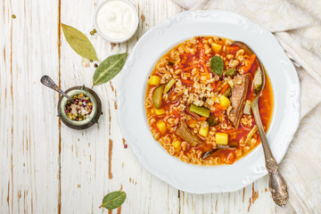 Traditional Russian soup Rassolnik beef with pickled cucumbers, potatoes, carrots, onions, tomatoes, pearl barley in bowl on wooden table. Top view. Copy space. Selective focus