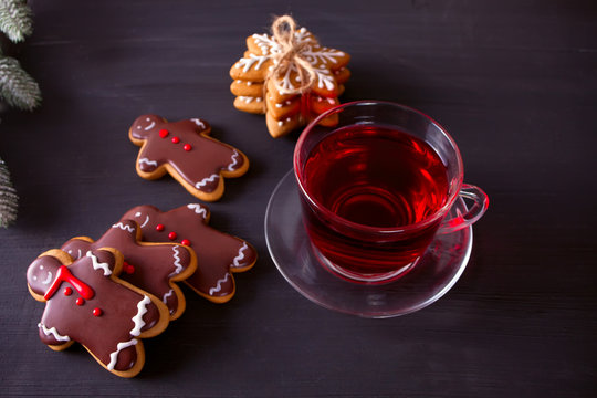 Christmas Cookies Funny Gingerbread Man And Snowflakes And Cup Of Tea On The Black Wooden Table.