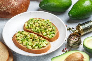 Slices of rye bread with avocado and spices colorful peppers and large sea salt, black sesame. Guacamole.  Sandwiches and ingredients on the table