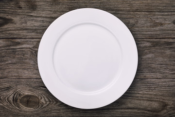 White empty ceramic plate on wooden table, top view. Food background
