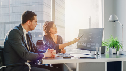 Female Top Manager and Male Businessman Sitting at the Desk Having Discussion and Working on a Desktop Computer, Solving Problems Successful People in Modern Stylish Office with Big City District View