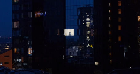 Fototapeta na wymiar Aerial Shot: From Outside into Office Building with Businessman Looking out of the Window. Beautiful Shot of The Financial Business District Skyscrapers in the Evening. 