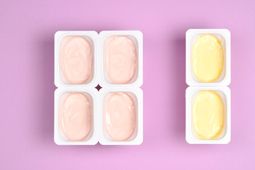 Plastic cup with tasty yogurt on lilac background. Top view. Space for text or design.