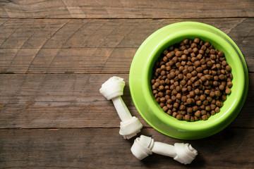 Dog bones and dog food on bowl on wood table background