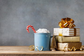 Winter lifestyle with cup of hot cocoa with marshmallows and Christmas gift or present boxes and...