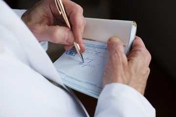 Closeup of a doctor writing a prescription on a blue prescription pad.