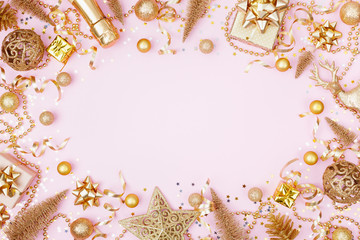 Christmas background with golden gift or present box, champagne and holiday decorations on pink pastel table top view. Greeting card. Flat lay style.