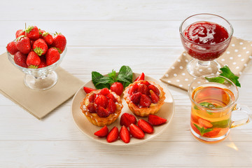 Tea drinking with tartlets and cakes with strawberries