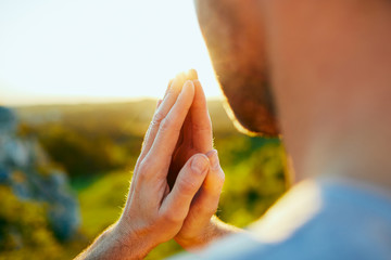 Closeup of man prying outdoors in the nature