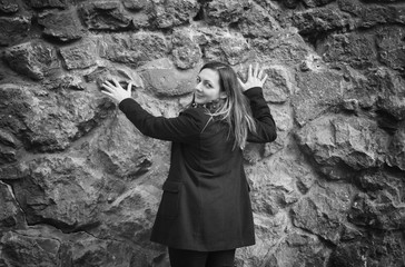 girl in hooded jacket outside. girl in hood and coat with baggage near stone wall in autumn season