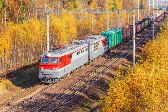 Fototapeta Long freight train approaches to the station at autumn day time.