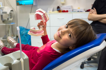 A girl in a dentist office is showing her jaws. Medicine, dentistry and health care.