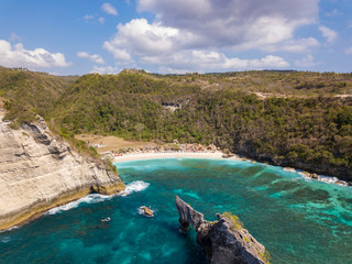 Fototapeta na wymiar Aerial view to beautiful Atuh beach with buildings, sunbeds and hindu temple. Turquoise ocean water. Photo from drone. Nusa Penida, Bali, Indonesia