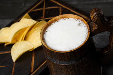 Beer in a wooden mug with chips on the board