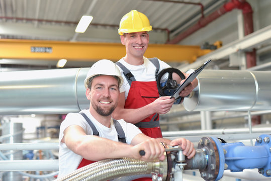 Mechanics repair a machine in a modern industrial plant - profession and teamwork - portrait group workman