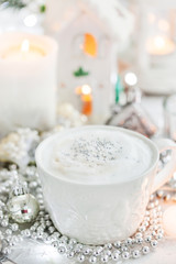 White cup of hot cappuccino coffee on holiday white and silver background, Christmas concept