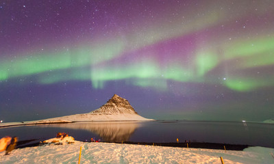 Colorful Aurora Borealis or better known as The Northern Lights and winter milky way over Kirkjufell, Iceland