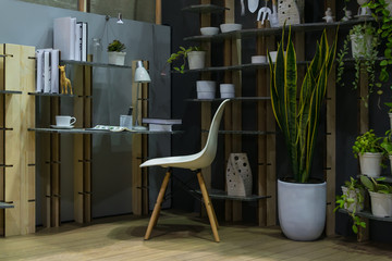 Modern compact working desk with equipment of gardening on shelf and black wall in house interior...