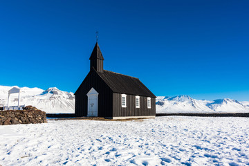 Budakirkja or better known as The Black Church view with blue sky during winter snow, Iceland