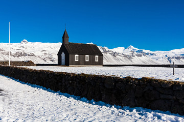 Budakirkja or better known as The Black Church view with blue sky during winter snow, Iceland