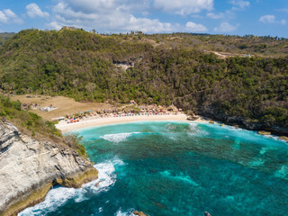 Aerial view to beautiful Atuh beach with buildings, sunbeds and hindu temple. Turquoise ocean water. Photo from drone. Nusa Penida, Bali, Indonesia