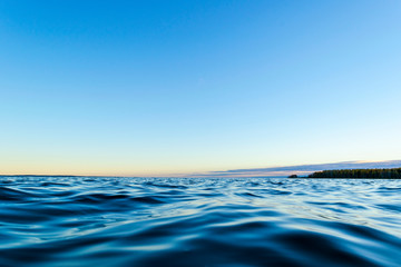Water surface. View of a Sunset sky background. Dramatic gold sunset sky with evening sky clouds over the sea. View of a Crystal clear sea water texture. Landscape. Small waves. Water reflection